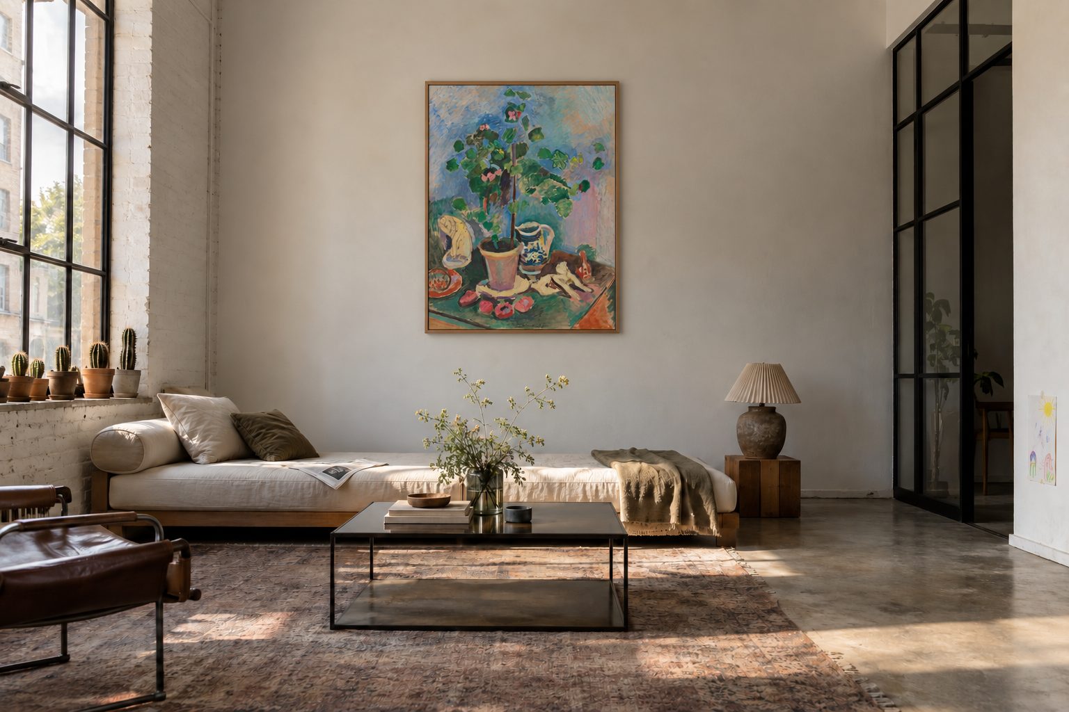 Séjour d'atelier avec un canapé bas sous une verrière, une nature morte de Matisse encadrée accrochée au centre d'un mur de brique blanchie, prête à recevoir deux pièces compagnes